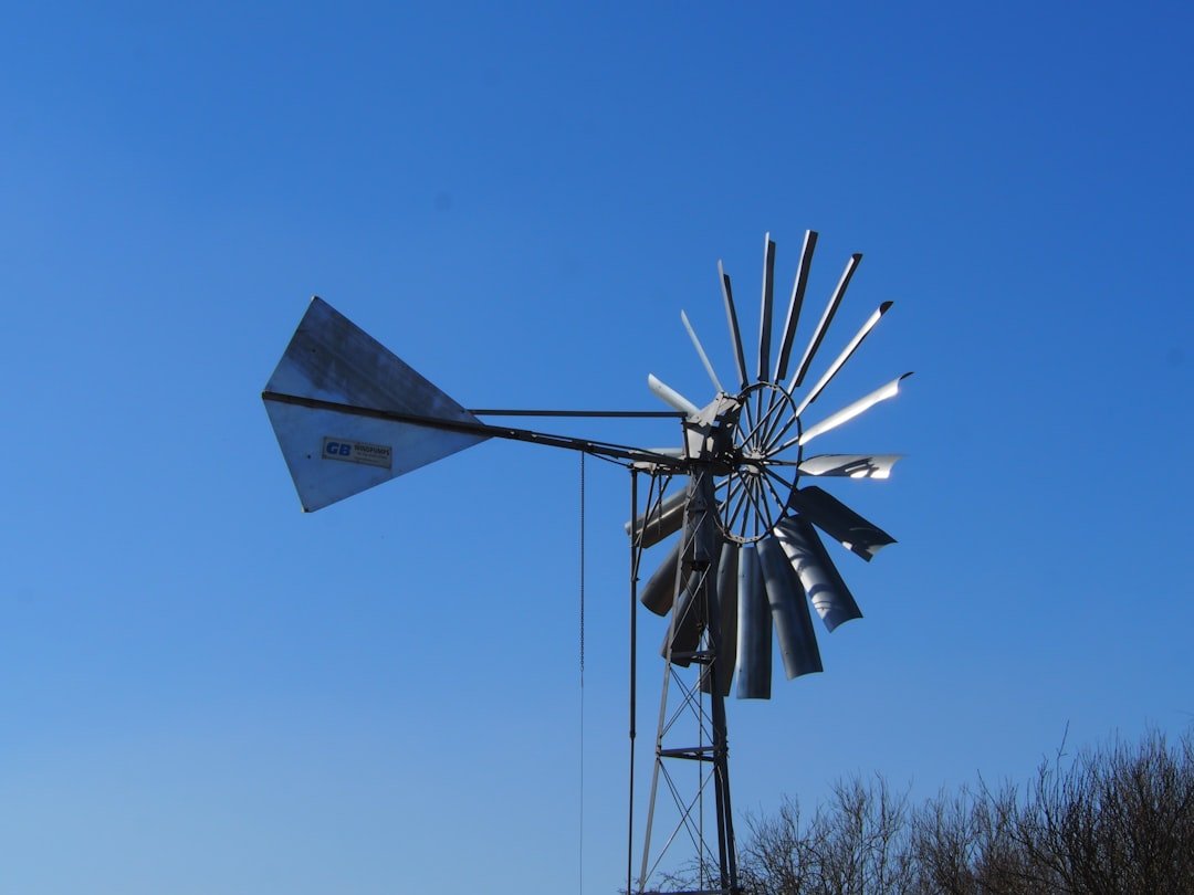 a-metal-windmill-against-a-clear-blue-sky-7phauj5edhm
